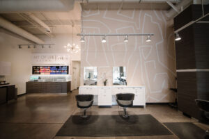 Modern hair salon interior in Waukee and Urbandale with two black chairs, product display, balayage, highlights, hair extensions.