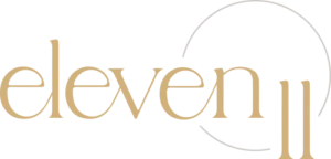 - Art of Life Salon & Spa at Urbandale and Waukee, IA The image features "eleven" in gold serif font—suggesting the best salon in Waukee & Urbandale for balayage, highlights, hair extensions, bridal hair, and permanent jewelry—accented by two vertical gold lines and a partial gold circle on a black background. - Art of Life Salon & Spa at Urbandale and Waukee, IA