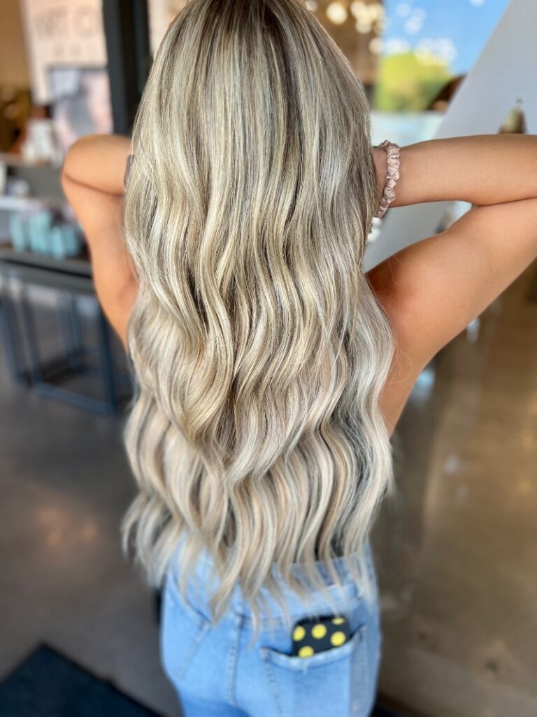 - Art of Life Salon & Spa at Urbandale and Waukee, IA A client with long, wavy blonde hair—perfect for balayage, highlights, or extensions at the best salon in Waukee or Urbandale. - Art of Life Salon & Spa at Urbandale and Waukee, IA