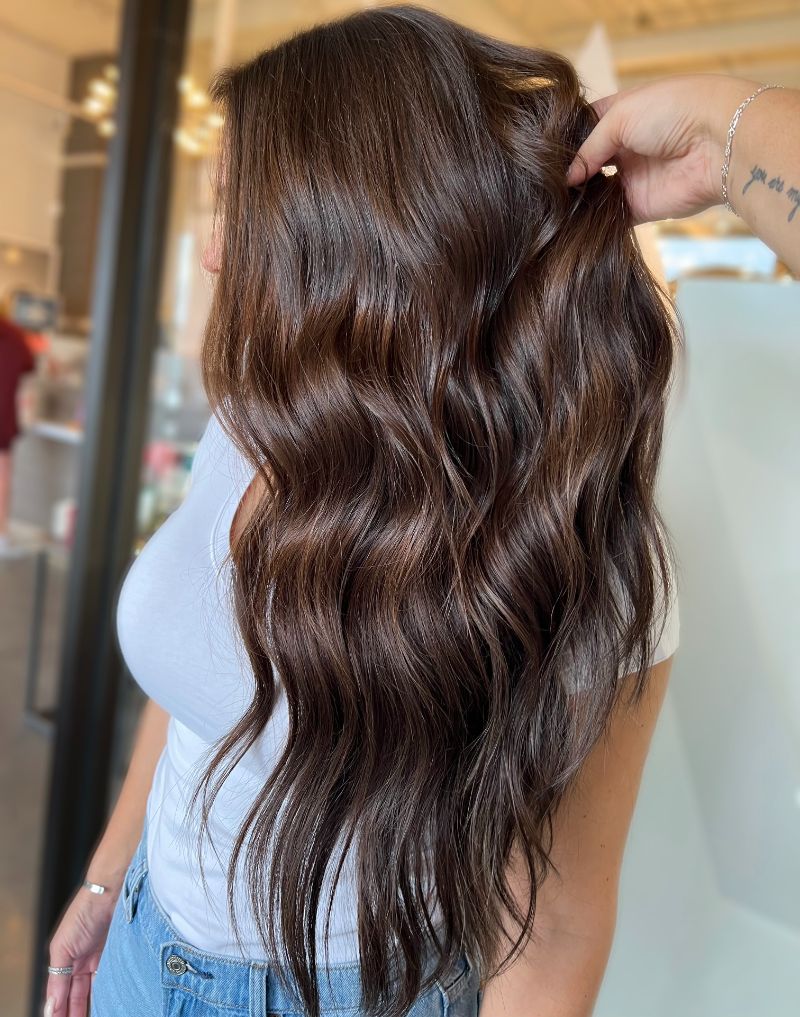 - Art of Life Salon & Spa at Urbandale and Waukee, IA Client with long, wavy, dark brown hair in a white shirt and blue jeans getting balayage and highlights at best salon in Waukee. - Art of Life Salon & Spa at Urbandale and Waukee, IA