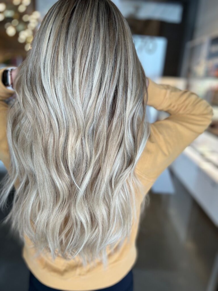 - Art of Life Salon & Spa at Urbandale and Waukee, IA Woman with long, wavy, blonde hair and highlights, wearing a yellow top at the best salon in Waukee for balayage and bridal hair. - Art of Life Salon & Spa at Urbandale and Waukee, IA